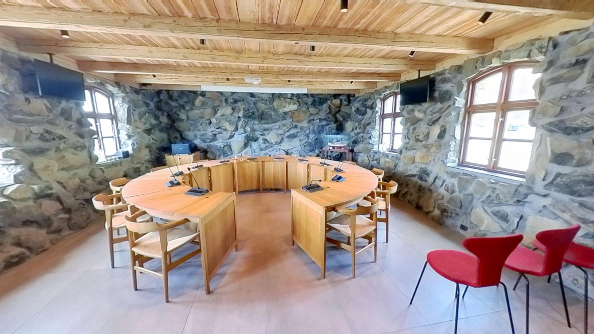 Inside Runavík's municipal council chamber — a circular wooden table with microphones, ringed by public seating