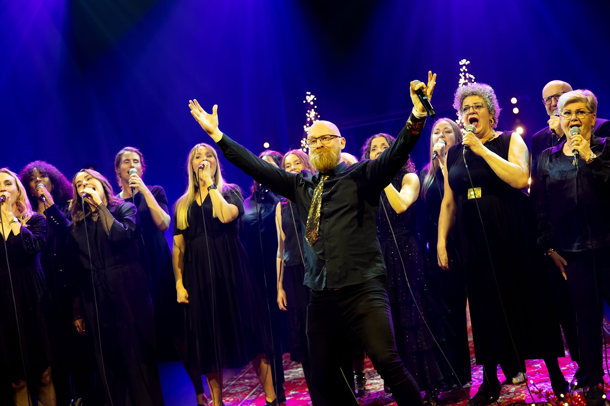 A choir performing on stage under stage lighting
