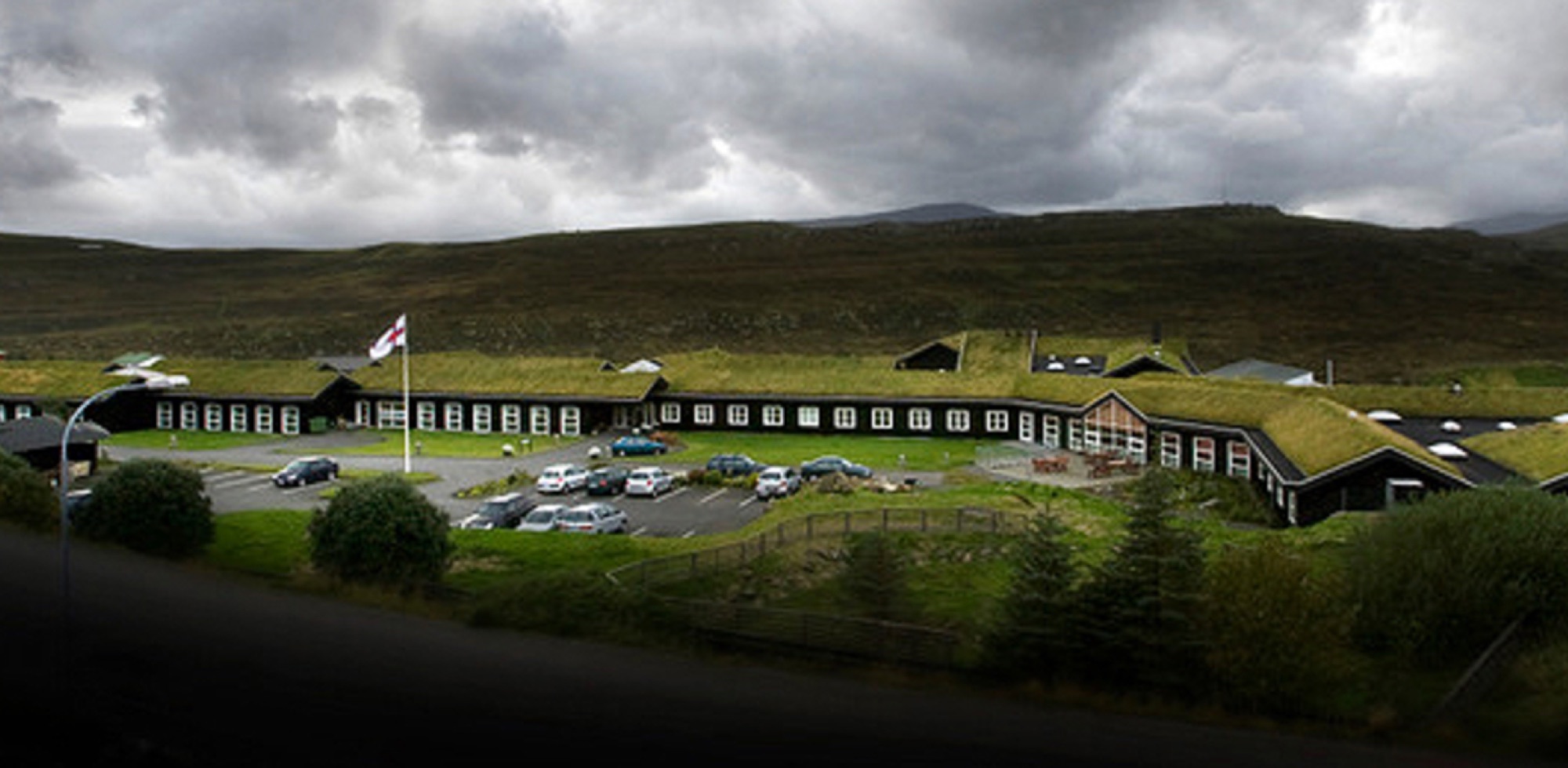 Eysturoyar røktar- og ellisheim, the care and nursing home, with the Faroese flag and mountains behind