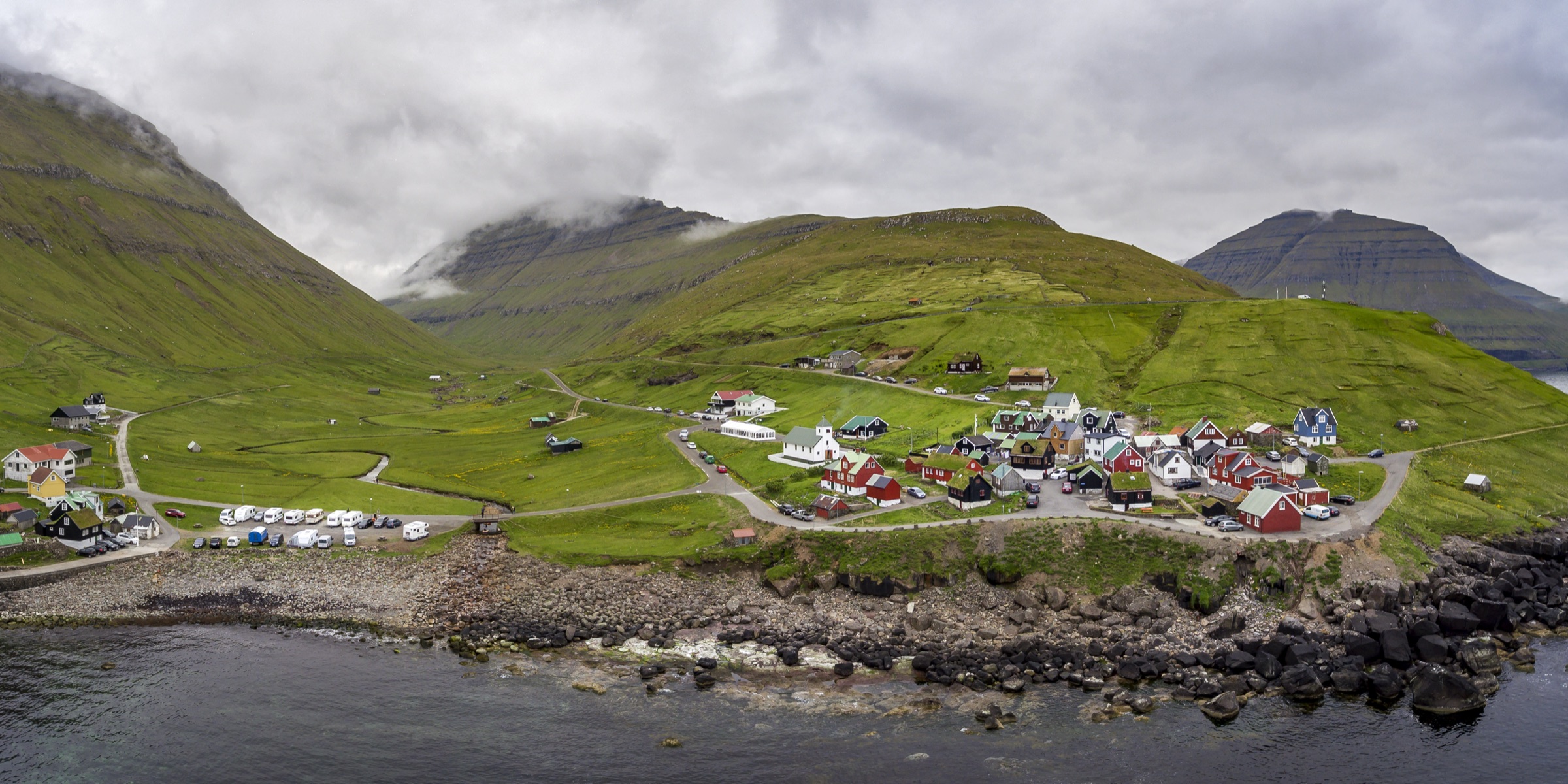 The village of Elduvík by the sea, with colourful houses beneath steep green mountains