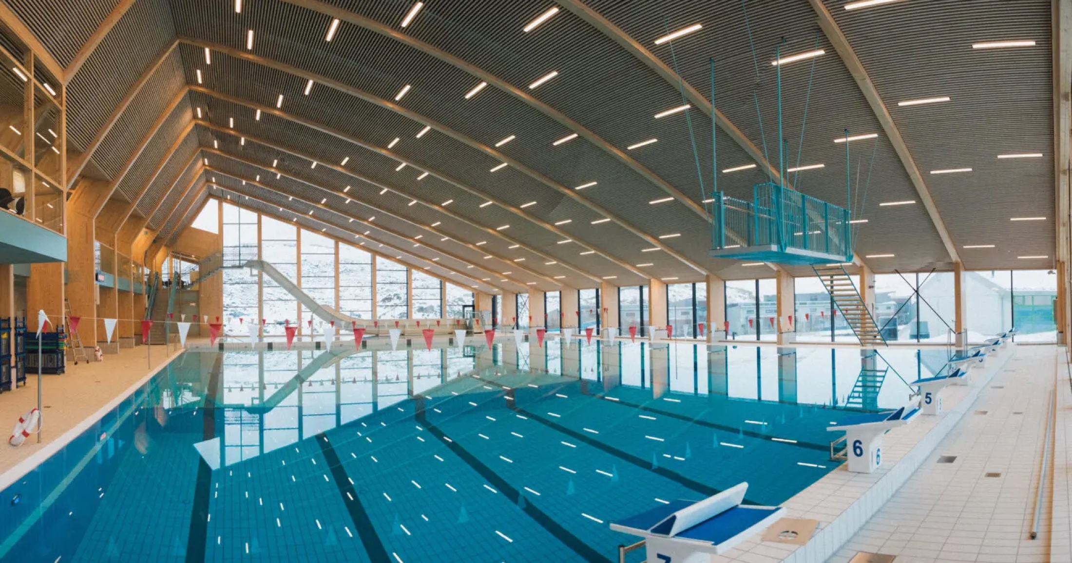 Interior of Bylgjan, the new indoor swimming pool, with lane pool, diving platform and mountain views through the glass