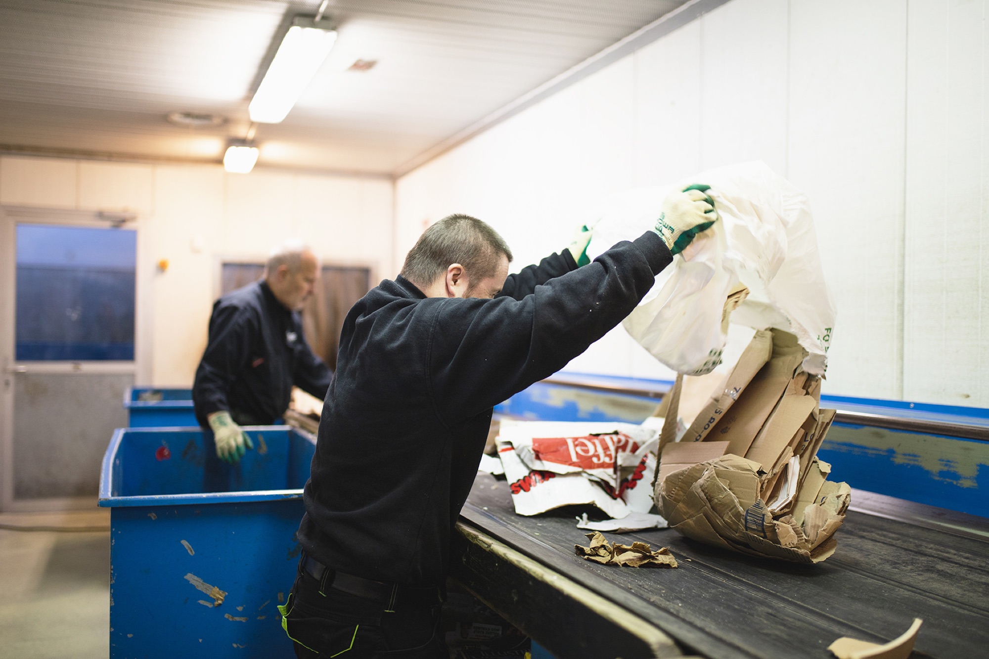 Workers sorting cardboard and recycling at a waste facility